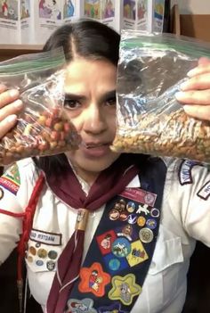 a woman in uniform is holding up a bag of peanuts and looking at the camera