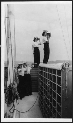 black and white photograph of two women on a boat looking through binoculars at the ocean