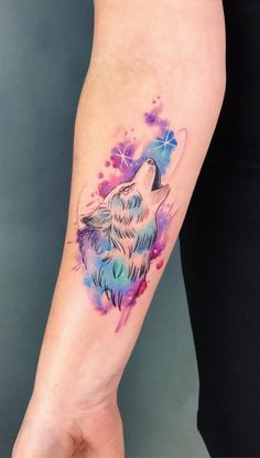 a person with a tattoo on their arm holding a small dog's head in the air