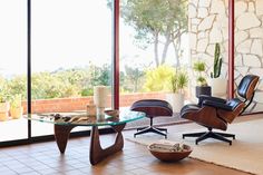 an empty living room with a glass top table and chairs in front of large windows