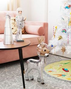 a living room with a christmas tree and toy deer on the floor in front of it