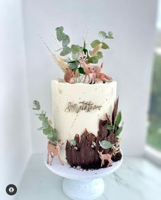 there is a cake decorated with animals and plants on the top of this cake stand