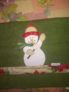 a snowman with a red hat and scarf on it's head is standing in front of a green wall