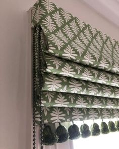 a green and white patterned roman blind with tassels