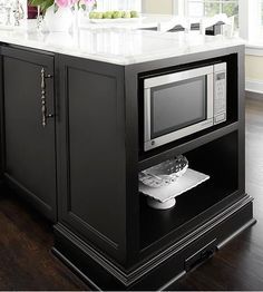 a kitchen island with a microwave on it and flowers in vases sitting on top