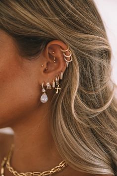 a woman with blonde hair wearing gold ear cuffs