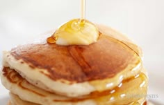 a stack of pancakes with butter on top and syrup being drizzled over them