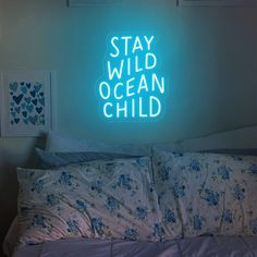 a neon sign that reads stay wild ocean child on the wall above a bed in a bedroom