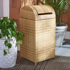 two planters sitting on the ground next to a basket and toilet paper dispenser