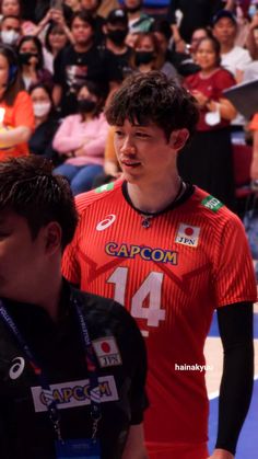 two young men standing next to each other in front of a group of people on a court