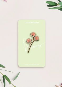 the little buddies enamel pin badge is shown on a green background with pink flowers