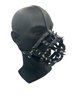 a mannequin head with spiked spikes on it's face and black leather straps