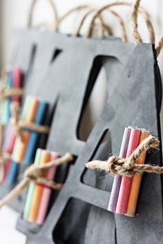 several colored candles are tied up to a black bag with twine on the handles