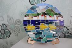 a colorful mosaic plate sitting on top of a white table next to a flowery wallpaper