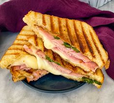 a grilled ham and cheese sandwich is on a blue plate with a purple napkin