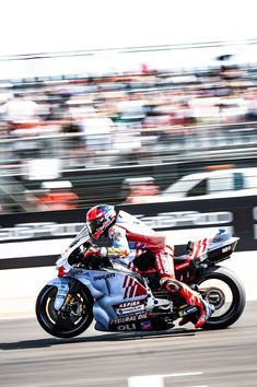 a man riding a motorcycle on top of a race track in front of a crowd