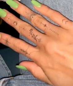 a woman's hand with green fingernails and tattoos on it