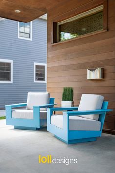 two blue chairs sitting next to each other in front of a house