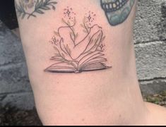 a tattoo on the leg of a woman with an open book and skull behind it