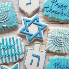 decorated cookies with blue and white icing are arranged on a wooden surface, including menorah