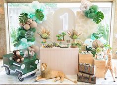 a jungle themed first birthday party with balloons, decorations and animals on the table top