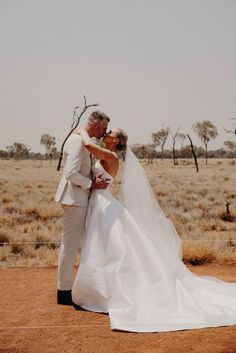 a bride and groom kissing in the desert