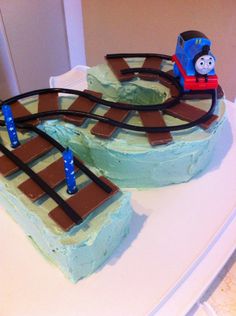 a thomas the train birthday cake with chocolate tracks and blue icing on it's sides