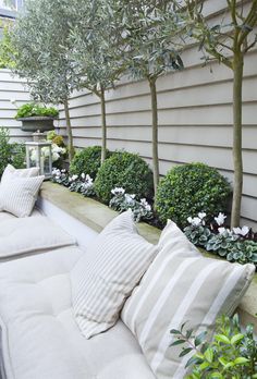 an outdoor seating area with pillows and plants