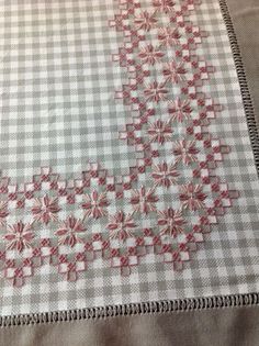 a quilted table runner with red and white flowers on it's edges, sitting on a bed