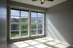 an empty room with a ceiling fan and large windows overlooking the mountains in the distance