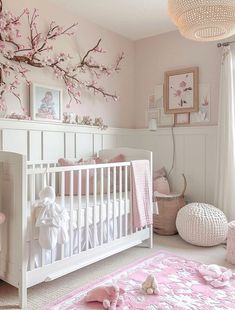 a white crib in a pink and white nursery with cherry blossoms on the wall