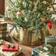 a christmas tree in a pot with presents under it and wrapped gifts around the base