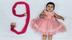 a baby girl wearing a pink dress next to a red headband and shoe clips