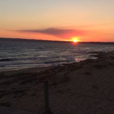 the sun is setting over the water at the beach