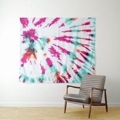 a chair sitting in front of a wall with a tie - dyed tapestry hanging on it