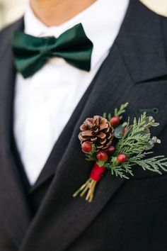 a man in a suit and bow tie wearing a pine cone boutonniere