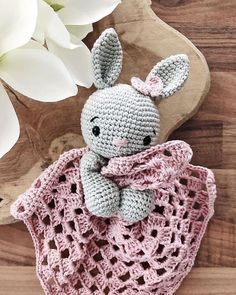 a crocheted stuffed animal sitting on top of a wooden table next to white flowers