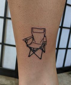 a small tattoo on the leg of a person with a chair in front of them