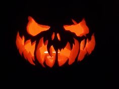 a carved jack o lantern in the dark with its mouth open and eyes glowing orange