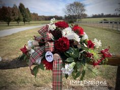 a bouquet of red and white flowers sitting on top of a wooden fence in front of a field