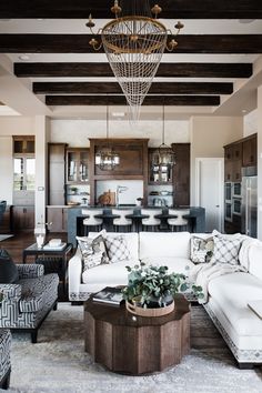 a living room filled with furniture and a chandelier hanging over the top of it