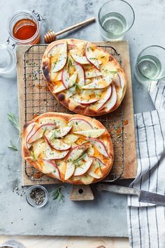 two pizzas sitting on top of a wooden cutting board