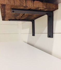 the shelf is made out of wood and has metal brackets on it's sides