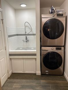 a washer and dryer in a small room with tile flooring on the walls