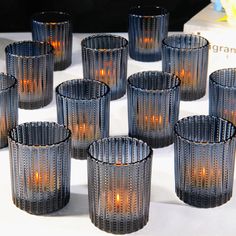 many candles are lit in glass cups on a table