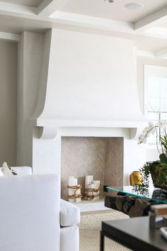 a living room with white furniture and a fireplace in the middle of it's walls