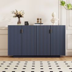 a blue cabinet sitting on top of a wooden floor next to a vase with flowers