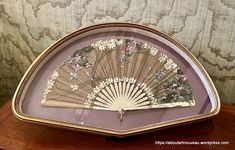 a decorative fan sitting on top of a wooden table