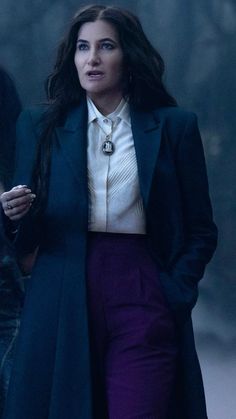 a woman in a long coat and purple pants