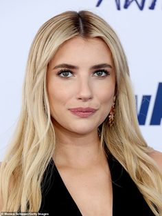 a woman with long blonde hair and blue eyes is looking at the camera while wearing a black dress